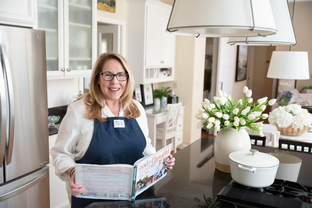 business woman holding a cookbook in a kitchen to show one of her hobbies